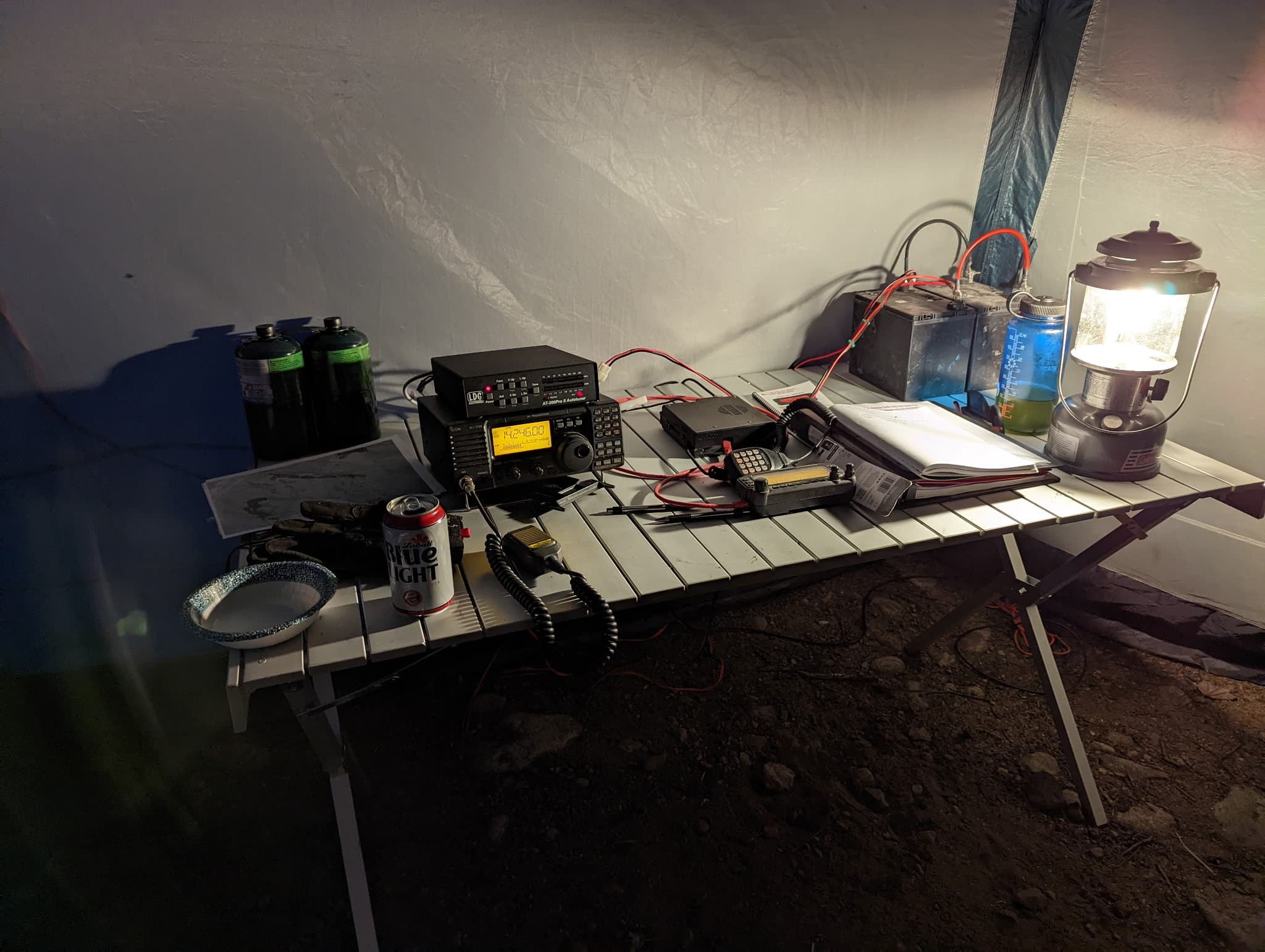 Night operating session in the field — HF rig, accessories, and the trusty Coleman lantern