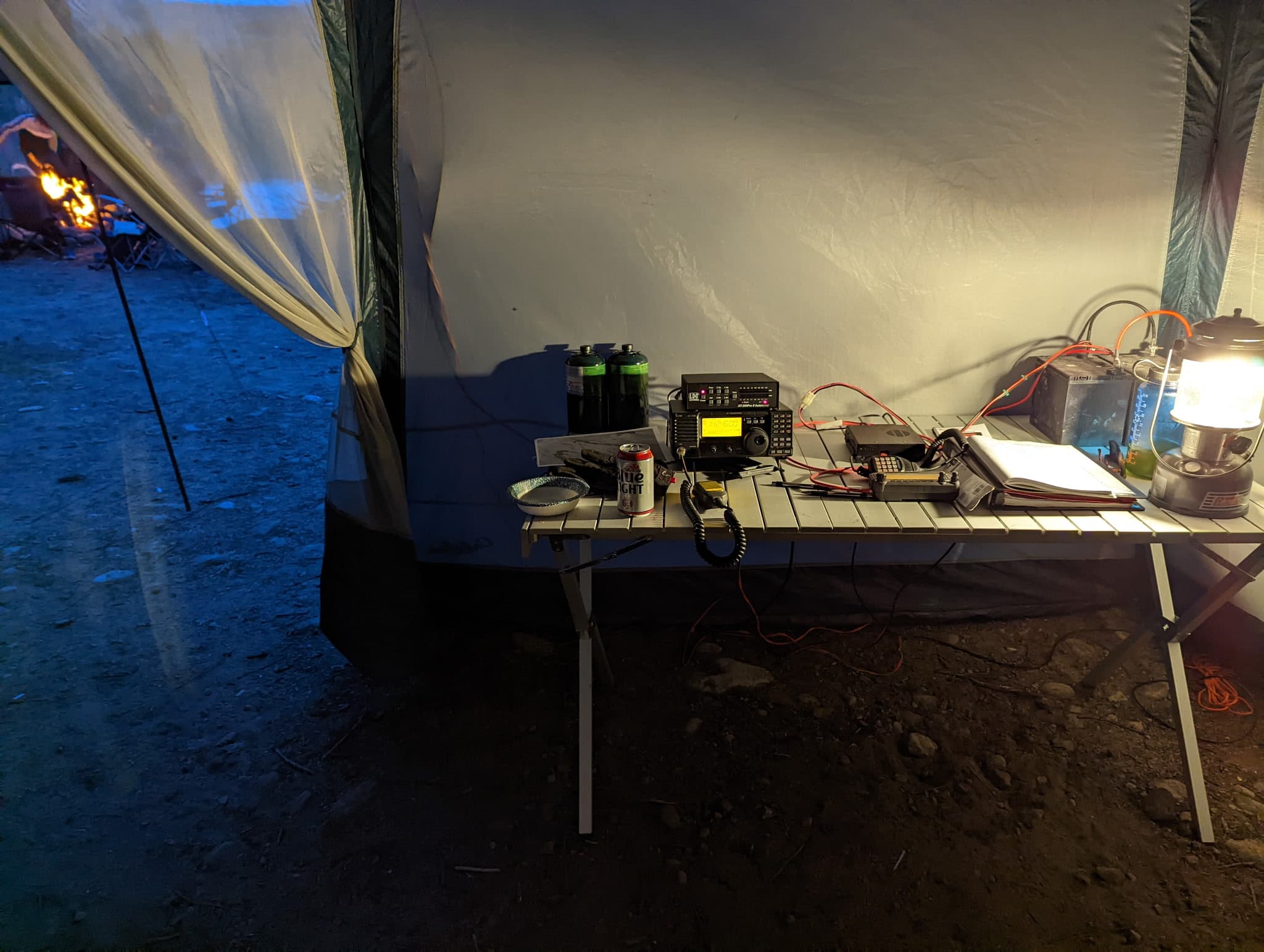 The radio tent after dark, campfire burning in the background